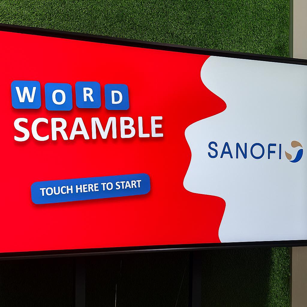 Guest playing word scramble game on large touchscreen at Dubai event with branded graphics and green artificial grass wall background.